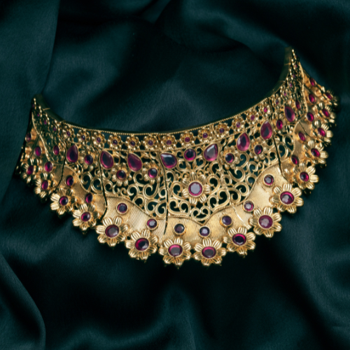 Intricate gold necklace displayed on emerald fabric